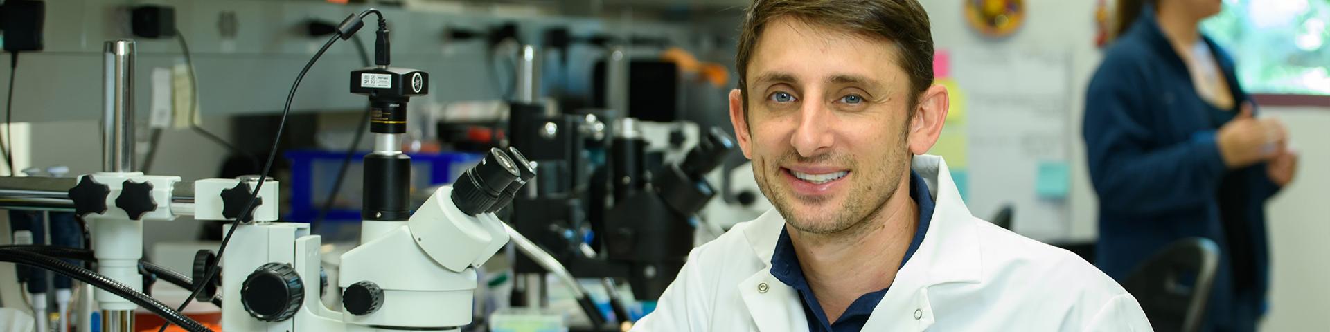 Professor in lab coat smiling at camera